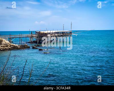 Plate-forme de pêche en bois soutenue par des pilotis en bois, structure traditionnelle Trabocco enjambant la côte rocheuse de l'Adriatique près de Rocca San Giovanni, Italie Banque D'Images