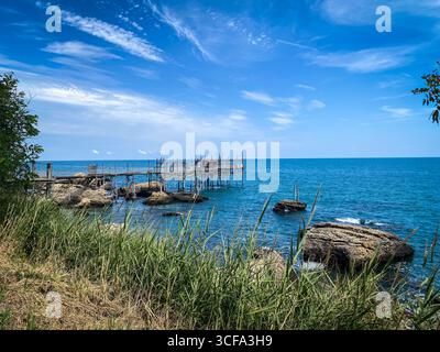 Plate-forme de pêche traditionnelle en bois s'étendant sur la côte rocheuse de l'Adriatique près de Rocca San Giovanni, caractéristique du patrimoine maritime de la région des Abruzzes Banque D'Images