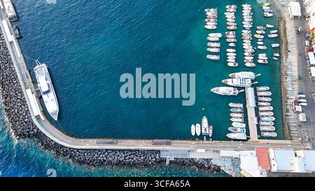 Des bateaux colorés amarrés à une marina animée sous un ciel bleu clair dans une ville côtière Banque D'Images