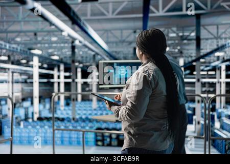 Développeur de logiciels de centre de données utilisant une tablette pour mettre à niveau les périphériques de stockage configurant pour une latence minimale dans les charges de travail d'IA. Expert INFORMATIQUE utilisant un appareil dans la salle des serveurs pour construire des réseaux neuronaux Banque D'Images