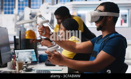 Technicien afro-américain dans l'usine de panneaux solaires utilisant des lunettes VR, optimisant les mises en page à l'aide d'un logiciel de CAO. Ouvrier d'usine photovoltaïque utilisant la technologie de réalité virtuelle pour faire des arrangements. Caméra A. Banque D'Images