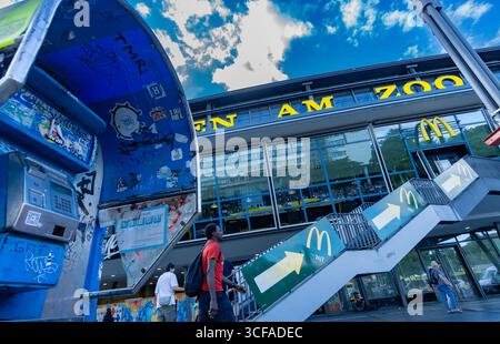 Berlin Zoologischer Garten station avec panneau visible, téléphone public cassé, graffitis et piétons dans une scène de rue urbaine. Banque D'Images