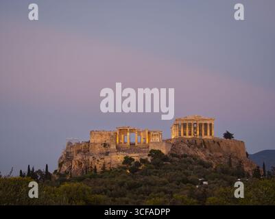 Ancienne Acropole illuminée au crépuscule, perchée sur une colline rocheuse avec un fond de ciel rose à Athènes Banque D'Images