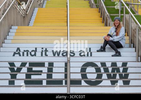 Wembley Park, Londres, Royaume-Uni. 22 août 2025. Les premiers fans de Coldplay arrivent à Wembley Park. Avant la série de concerts de groupes au stade de Wembley, à partir de ce soir, le super fan arrivant tôt, Aniko de Suisse, visite l'installation d'art public de Wembley Park, en collaboration avec Pantone, 'YELLOW 25' sur les marches espagnoles, un gradient de 58 pas de jaunes pour célébrer le 25e anniversaire de la chanson de Coldplay 'Yellow'. Crédit : Amanda Rose/Alamy Live News Banque D'Images