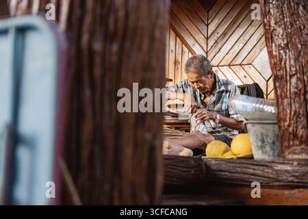 Artisan âgé fabriquant un balai de noix de coco traditionnel Banque D'Images