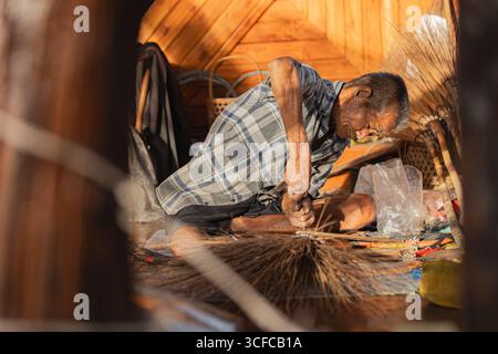 Vieux artisan thaïlandais fabriquant un balai traditionnel Banque D'Images