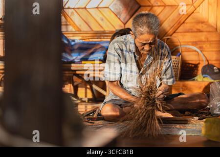 Vieux artisan thaïlandais créant un balai traditionnel Banque D'Images
