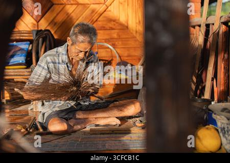 Vieux artisan thaïlandais tissant un balai fait à la main Banque D'Images