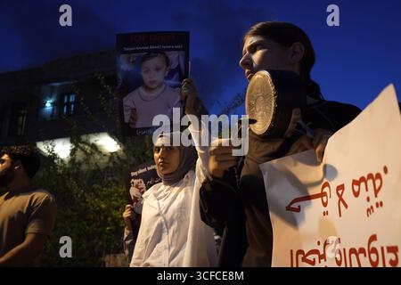 HAÏFA, ISRAËL - 21 AOÛT : des manifestants arabes israéliens et des militants de la paix ont frappé des pots alors qu'ils tenaient des pancartes condamnant la guerre, aux côtés de photos d'enfants palestiniens et de journalistes tués par l'armée israélienne à Gaza lors d'une manifestation contre la guerre d'Israël dans la bande de Gaza le 21 août 2025 à Haïfa, en Israël. Banque D'Images
