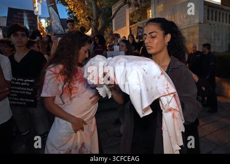 HAÏFA, ISRAËL - 21 AOÛT : les manifestants tiennent des colis enveloppés dans des enveloppes, symbolisant les corps d'enfants palestiniens tandis que d'autres manifestants arabes israéliens et militants pour la paix tiennent des pancartes condamnant la guerre, aux côtés de photos d'enfants palestiniens et de journalistes tués par l'armée israélienne à Gaza lors d'une manifestation contre la guerre israélienne dans la bande de Gaza le 21 août 2025 à Haïfa, Israël. Banque D'Images