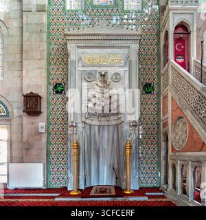 Mihrab orné, minbar, et tilework traditionnel d'Iznik à l'intérieur de la mosquée burundaise, turc : Burundguz Camii, à Kayseri, Turquie. Tapis rouges riches et détails dorés Banque D'Images