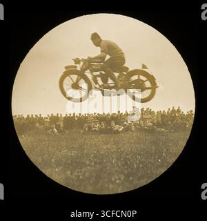 Une vue d'une moto sautant devant une foule de spectateurs à un endroit et événement inconnus, dans les années 1920-1930 L'événement et le lieu montrés sur cette photographie ne sont pas connus. Banque D'Images