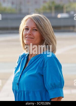 Femme en robe bleue pose à l'extérieur avec la main sur la hanche, souriant avec confiance à la caméra. Italie Banque D'Images
