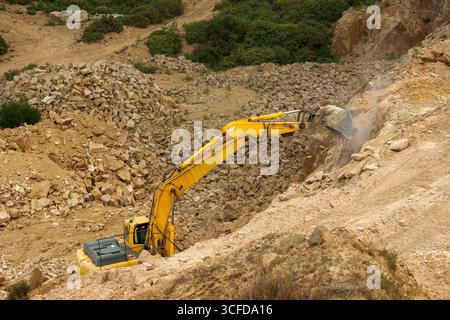 Hopeman Moray Coast Scotland carrière Clashach excavatrice jaune industrielle avec bras de godet étendu enlevant une grande dalle de grès Banque D'Images