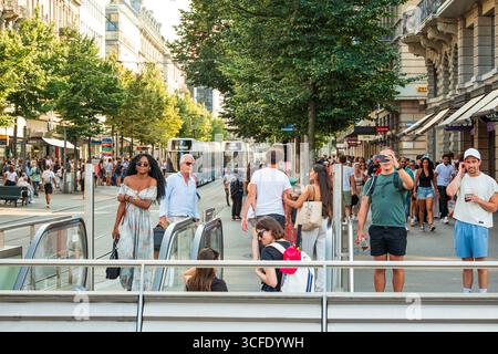 Zurich, Suisse, 19 août 2025. Foules de touristes et de navetteurs sur Bahnhofstrasse près du passage piétonnier. Journée d'été ensoleillée, tram dans le stati Banque D'Images