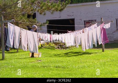 Femme de la communauté anabaptiste séchant le linge sur la corde à linge dans la cour arrière dans le Vermont, États-Unis, approx. 1996 Banque D'Images