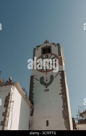 Faro, Algarve, Portugal – 2025.07.02 – gros plan d’une tour historique de l’horloge de la cathédrale datant de 1809 avec des chiffres romains et une cloche sur un ciel bleu clair. Banque D'Images