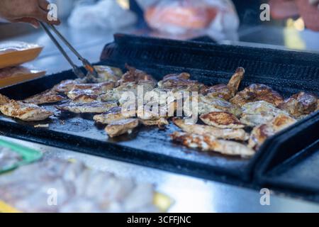 Gros plan sur la cuisson et la rotation du poulet sur un grand barbecue extérieur avec charbons chauds Banque D'Images