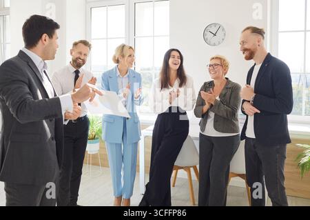 L'équipe célèbre le succès dans Modern Office lors d'une réunion matinale avec Smiles and Applause Banque D'Images