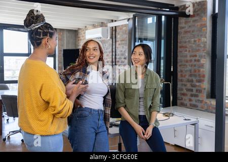 Diverses collègues féminines discutant du projet autour du bureau avec des écrans d'ordinateur et une souris dans le bureau Banque D'Images