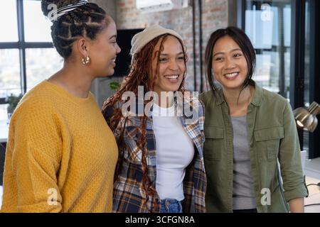 Diverses collègues féminines debout ensemble à l'intérieur du bureau avec moniteur d'ordinateur et plante en pot Banque D'Images