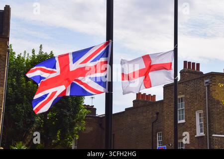 Londres, Royaume-Uni. 22 août 2025. Un drapeau anglais avec la Croix de Saint-Georges et un Union Jack sont attachés aux lampadaires à Clerkenwell. Les drapeaux anglais et les syndicalistes sont de plus en plus installés par les gens sur les lampadaires de rue à travers l'Angleterre dans le cadre d'une campagne « patriotique », mais beaucoup remettent en question les motifs, car des drapeaux ont commencé à apparaître au milieu de la vague actuelle de protestations contre le placement des migrants et des demandeurs d'asile dans des hôtels. Crédit : Vuk Valcic/Alamy Banque D'Images