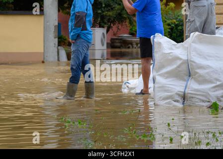 Les résidents pataugeaient dans les eaux profondes d'une rue inondée, essayant d'évaluer les dommages et de demander de l'aide dans une communauté résidentielle voisine. Banque D'Images