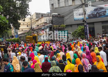 Dhaka, Dhaka, Bangladesh. 23 août 2025. Des ouvriers de vêtements chics bloquent une route exigeant le paiement des salaires dus et la réouverture de l'usine après sa fermeture soudaine sans préavis, dans la région de Tejgaon à Dhaka, au Bangladesh, le 23 août 2025. L'usine employait environ 1 200 ouvriers de l'habillement. L'industrie du vêtement, un moteur crucial de l'économie d'exportation du Bangladesh, est actuellement aux prises avec une série de défis qui ont conduit à un ralentissement important. Au cours de l'année écoulée, au moins 76 usines de confection ont fermé leurs portes, poussant plus de 50 000 travailleurs, principalement des femmes, à quitter leur emploi. Indus Banque D'Images