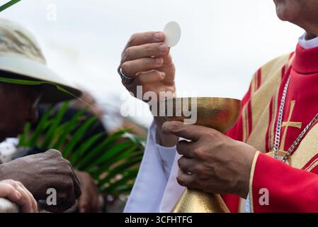 Prêtre catholique distribuant des gaufrettes de communion aux fidèles le dimanche des Rameaux. Salvador, Brésil Banque D'Images