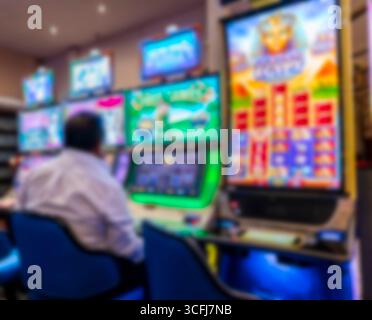 Homme jouant à la machine à sous à l'intérieur du hall de casino éclairé Banque D'Images