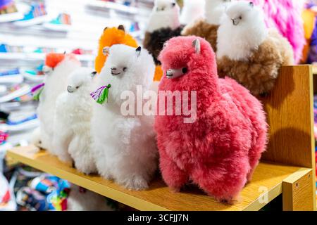 Jouets en peluche d'alpaga colorés faits à la main à partir de laine andine, exposés comme souvenirs traditionnels dans un marché de Cusco, représentant la culture et l'artisanat péruviens. Banque D'Images