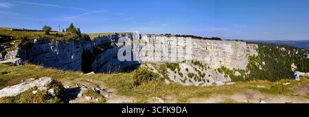 Panoramique des parois rocheuses escarpées du creux du Van, connu sous le nom de « Grand Canyon » suisse sous la lumière chaude du soleil matinal d'automne sous un ciel bleu, Suisse Banque D'Images