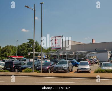 Porec, Croatie - 31 mai 2025 : parking occupé du supermarché Kaufland rempli de voitures sous le ciel bleu. Architecture commerciale moderne avec rouge distinctif Banque D'Images
