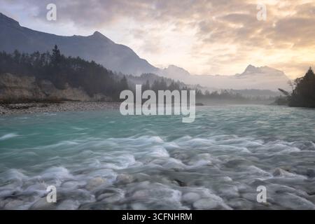 Rivière Soča turquoise coulant dans la vallée alpine au lever du soleil près de Bovec, Alpes juliennes, Slovénie Banque D'Images