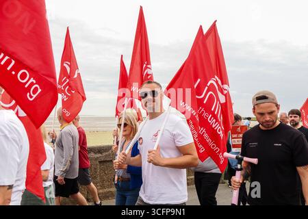Cleethorpes, Royaume-Uni . 24 août 2025. De gauche à droite, les manifestants défilent vers l'avant en brandissant des drapeaux pendant le rassemblement de protestation de Save Lindsey Oil Refinery – manifestation Cleethorpes contre la fermeture de Central Promenade. Crédit : Freddie Yeo/Alamy Live News Banque D'Images