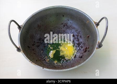 Un Kadhai sale, ou Karahi, avec des restes de taches noires et de l'huile de cuisson brûlée après avoir frit de la viande, du poulet et du poisson. Banque D'Images
