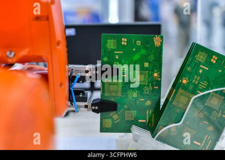 Système d'automatisation moderne de bras de robot déplaçant les cartes de circuit imprimé dans une usine, concept de robot industriel Banque D'Images