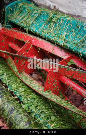 Gros plan d'une tondeuse rotative manuelle avec de l'herbe coupée sur les lames. Banque D'Images