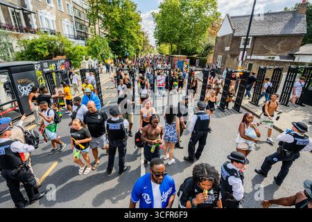 Londres, Royaume-Uni. 24 août 2025. Détecteurs de métaux de la police sur le chemin vers le bas de la station de Notting Hill - le dimanche du carnaval de Notting Hill, traditionnellement la journée des enfants. L'événement annuel dans les rues du Royal Borough de Kensington et Chelsea, pendant le week-end du jour férié du mois d'août. Il est dirigé par des membres de la communauté britannique des Antilles et attire environ un million de personnes chaque année, ce qui en fait l'un des plus grands festivals de rue au monde. Crédit : Guy Bell/Alamy Live News Banque D'Images