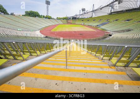 Vue centrale du stade depuis les escaliers sur les stands vides et la piste de course rouge, Parc olympique, Munich, Allemagne Banque D'Images