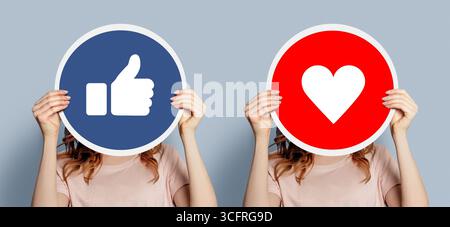 Comme concept. Les filles tenant une pancarte avec des pancartes semblables isolées sur fond gris. Bannière Web Banque D'Images
