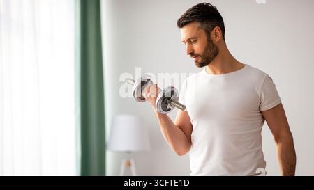 Gros plan de beau barbu homme faisant l'entraînement de haltères à la maison Banque D'Images