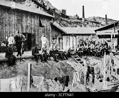 Image tirée de L’illustration (1916) montrant des prisonniers de guerre allemands reposant près de casernes à L’Estaque, à l’extérieur de Marseille. Capturés pendant la première Guerre mondiale, les prisonniers sont vus dans des conditions informelles avec le linge accroché à proximité. Ces images illustrent la vie quotidienne des prisonniers de guerre en France et reflètent les aspects pratiques et symboliques de la captivité en temps de guerre pendant la Grande Guerre. Banque D'Images