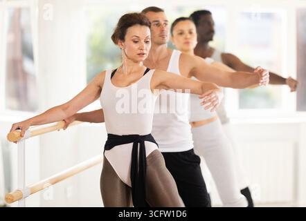 Ballerine exécutant le battement tendu jete à la barre de ballet à la classe de groupe Banque D'Images