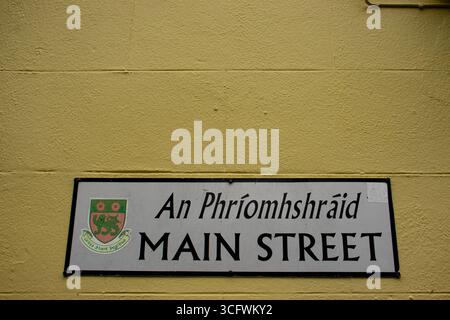 Un panneau sur un mur jaune indique main Street en anglais et en irlandais, dans la ville d'Athlone, dans le comté de Westmeath, en République d'Irlande. Banque D'Images