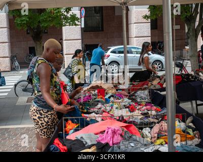 Cremona, Italie- 23 août 2025 marché en plein air animé dans la ville italienne avec divers acheteurs parcourant les étals remplis de vêtements et d'accessoires un Banque D'Images