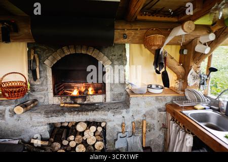 Cuisine rustique extérieure chaleureuse et accueillante avec cheminée en pierre à bois. Banque D'Images