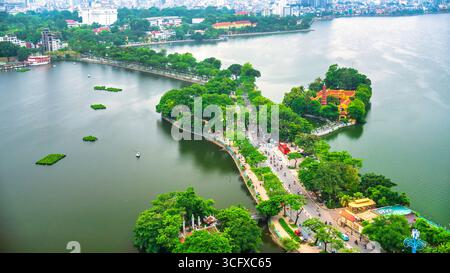Vue aérienne de la route traversant l'île Westlake avec rue bordée d'arbres verts, temple situé entre petite oasis. Un beau coucher de soleil dans la capitale Banque D'Images