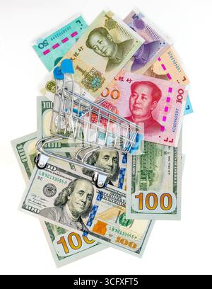 Mini panier sur des billets dispersés en dollars américains et en Yuan chinois. Concept des finances et du commerce internationaux. Banque D'Images