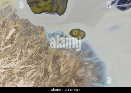 Vue aérienne des rivières tressées creusent des chemins complexes à travers les plaines glaciaires, contrastant avec le terrain rocheux et rocheux, les hautes terres de l'Islande. Banque D'Images